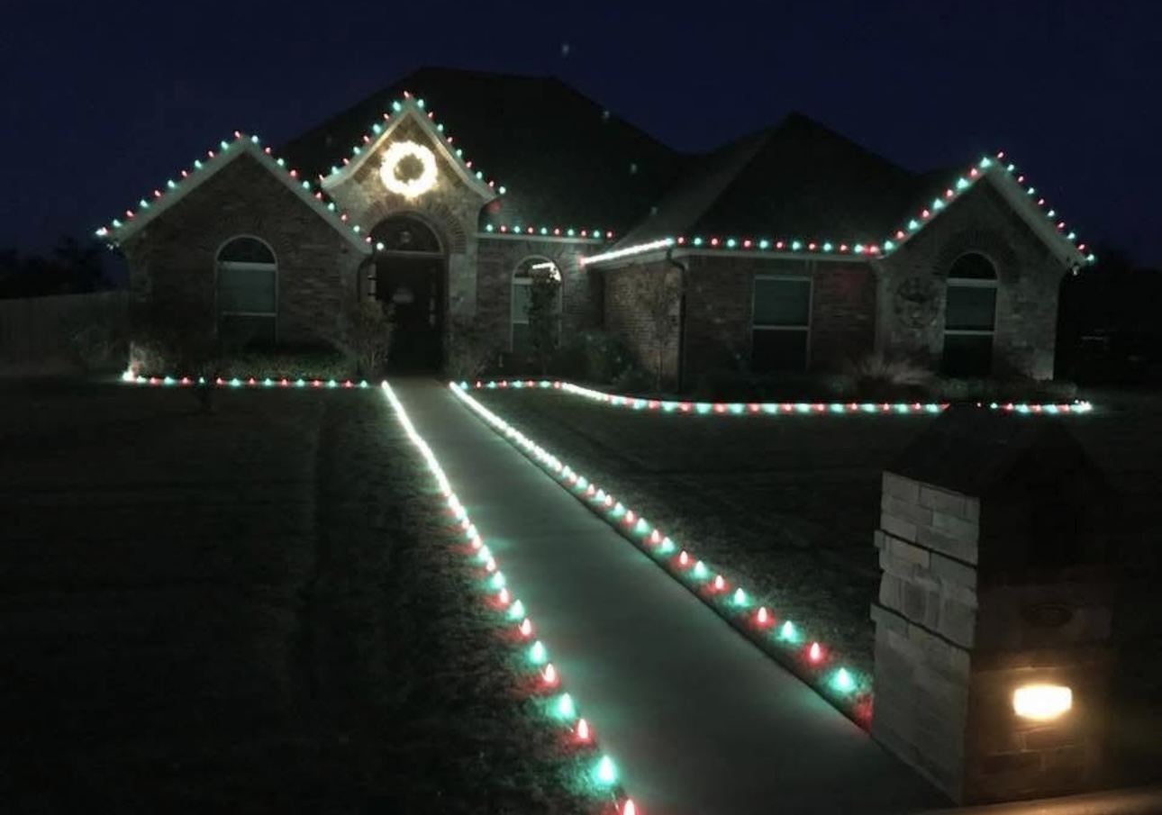 Home in red and green holiday lights with a glowing walkway at night